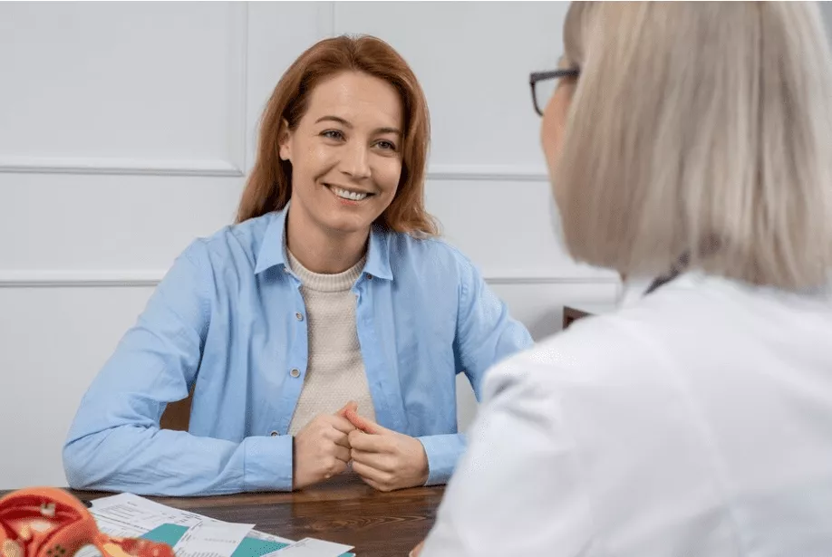A smiling woman talking with her clinician during a hormone therapy consultation